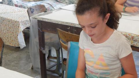 Youth cuts clay to make beads. 