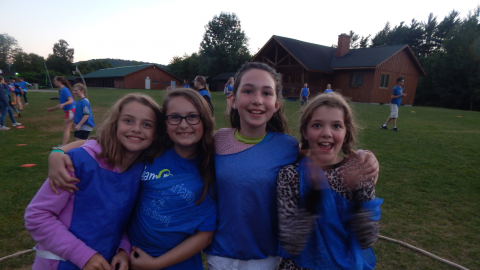 Four youth stand together in blue pinnies during a campwide game.