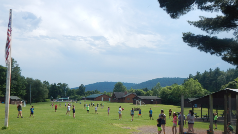 wide shot of camp showing campers scattered across the backstop, field, pool, etc.