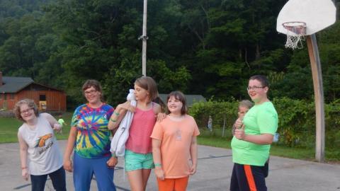 Youth standing on the basketball court smile for the camera. 