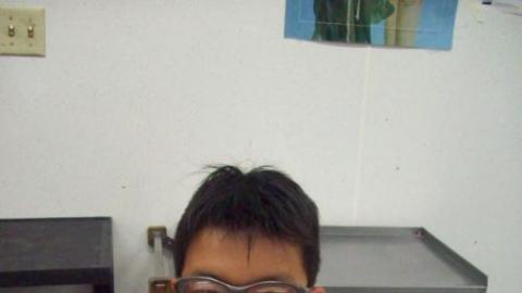 Camper smiles with a pepperoni pizza in front of him. 