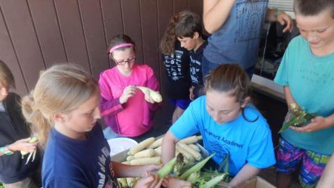 Youth husk corn to be used in a meal. 