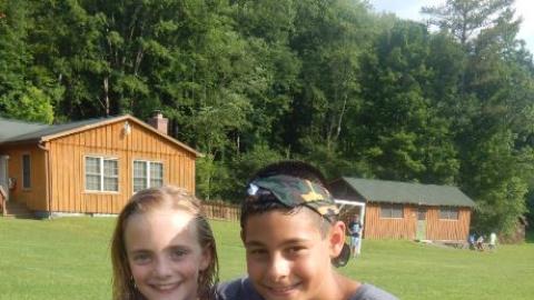 Three youth standing together and smiling for the camera. 