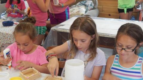 Youth working on an arts and crafts project with Popsicle sticks. 