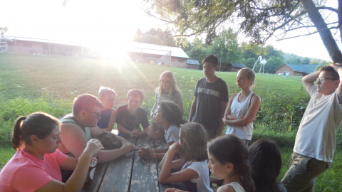 Platoon group gathered around a picnic table with counselor.