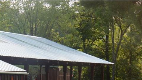 Youth sitting on the ground in a circle outside of the pavilion. 