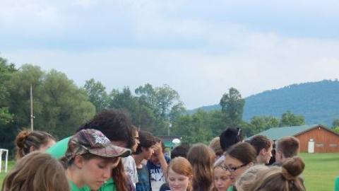 Youth standing around and putting food on their plates. 