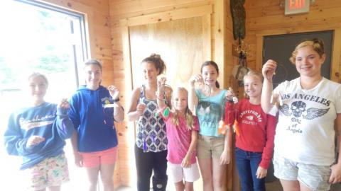 Youth hold up their dream catcher crafts. 