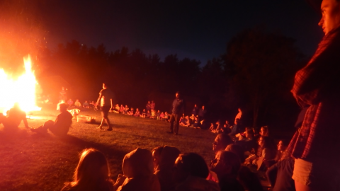 Youth seated around a large bonfire.