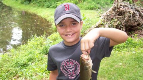 Youth holds up a freshly caught fish. 