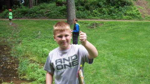 Youth holds up a freshly caught fish. 