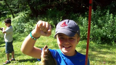 Youth holding up a freshly caught fish. 