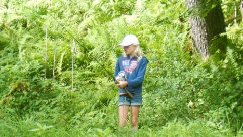 Camper fishing with a reflection of it in the water. 