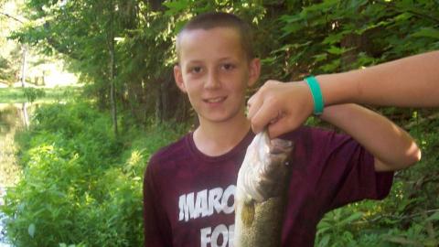 Youth holds up a freshly caught fish. 