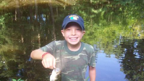 Youth proudly holds up a freshly caught fish. 