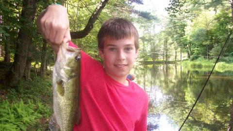 Youth holds up a freshly caught fish. 