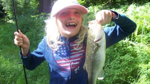 Youth proudly holds up a freshly caught fish. 