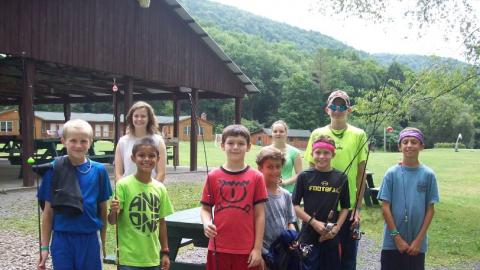 Youth standing for a photo with fishing poles in their hands. 