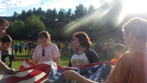 Youth working together to fold an American flag.