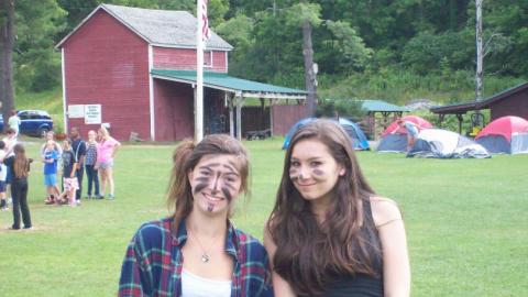 Youth smiling and wearing cat face paint. 