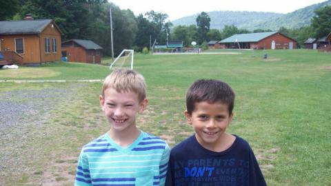 Two smiling youth stand next to each other. 