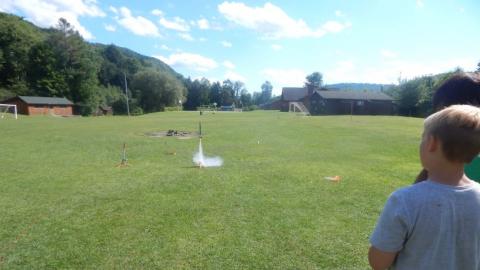 Camper watching a model rocket take off. 