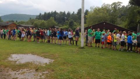 Youth stand in a line to get their food during an outdoors picnic. 