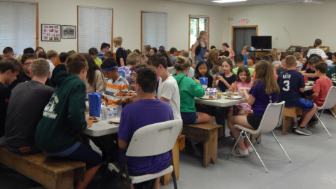Campers and counselors seated together for a family style meal.
