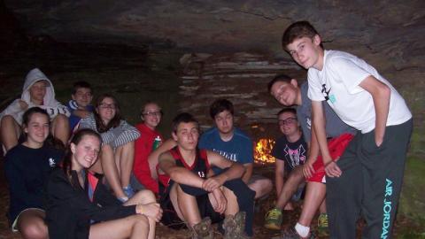 Youth sitting outside by a fire. 