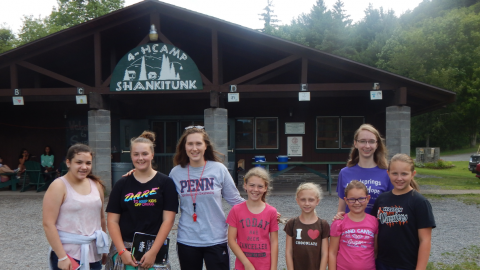 group of youth and counselor standing together in front of the dining hall.