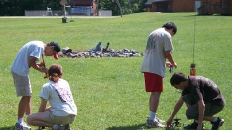 Two rocket launchers are being set with camper rockets. A camper and counselor work together on each station to ready the rockets for launch.