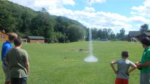 Campers watching model rockets launching. 