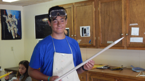 Youth displaying a long model rocket they have built.