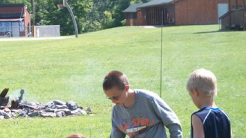 two campers work with a counselor to ready their rockets for launching.