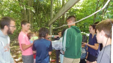 Youth helping each other through a rope obstacle. 