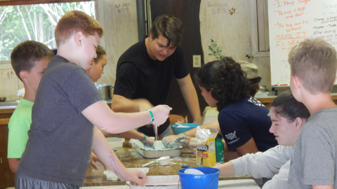 campers dip their hands into a bucket of slime.