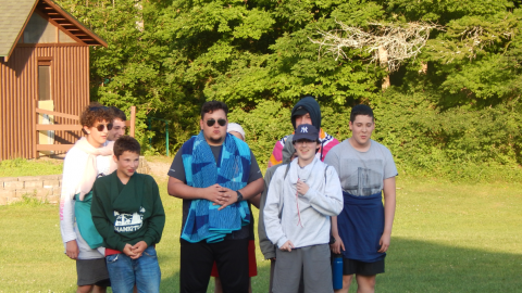 Cabin group standing together wearing hooded sweatshirts backwards.