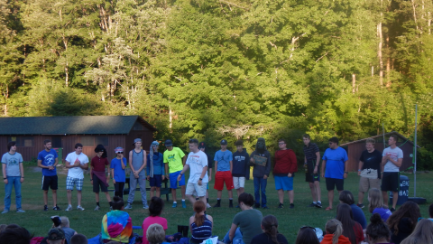 large group of staff in a line in front of seated campers.