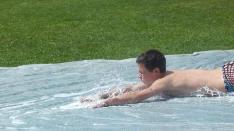 Youth going down a slip and slide face first. 