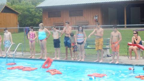 Youth standing on the side of the pool during a swimming lesson. 