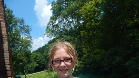Camper holding up a freshly rinsed tie-dye bandanna.