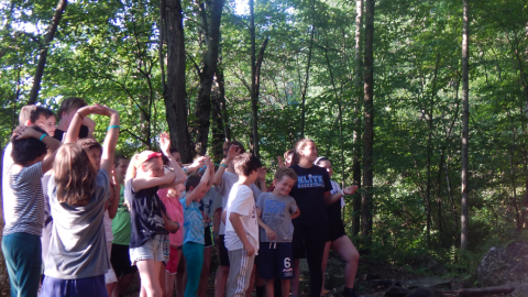 group of youth in a wooded area performing a skit.