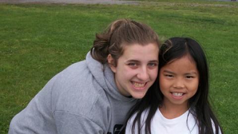 counselor and youth standing together holding a volleyball and smiling.