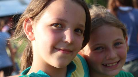 two campers with arms around each other's shoulders smiling