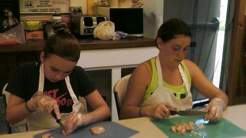 campers cutting food on cutting boards and wearing plastic gloves 