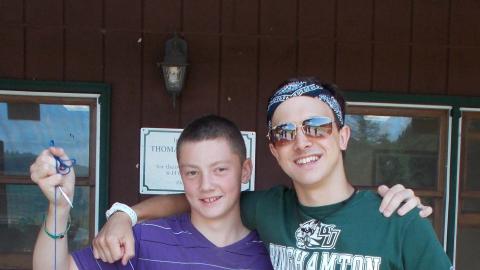 two youth standing with freshly caught fish on line