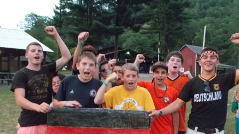 Campers cheering with raised fists while holding handmade German flag