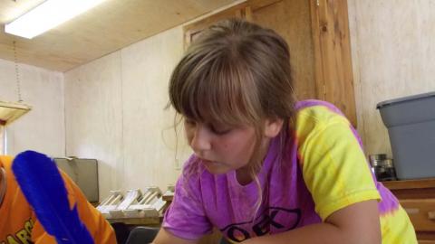 camper writing with feather pen on small piece of paper
