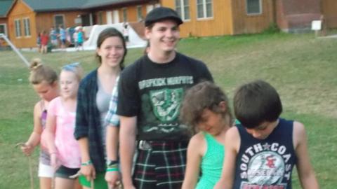 campers standing with one foot each on two wooden boards holding ropes and smiling at the camera or looking at their feet.