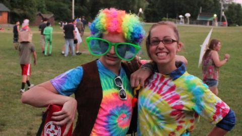 Staff wearing tie dye clothing and wig holding life guard float 